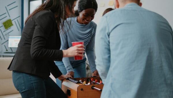 Group of colleagues playing at foosball table after work