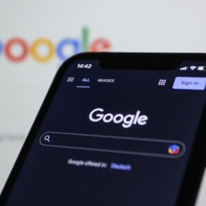 Smartphone screen showing Google search in dark mode with the Google logo in the background.